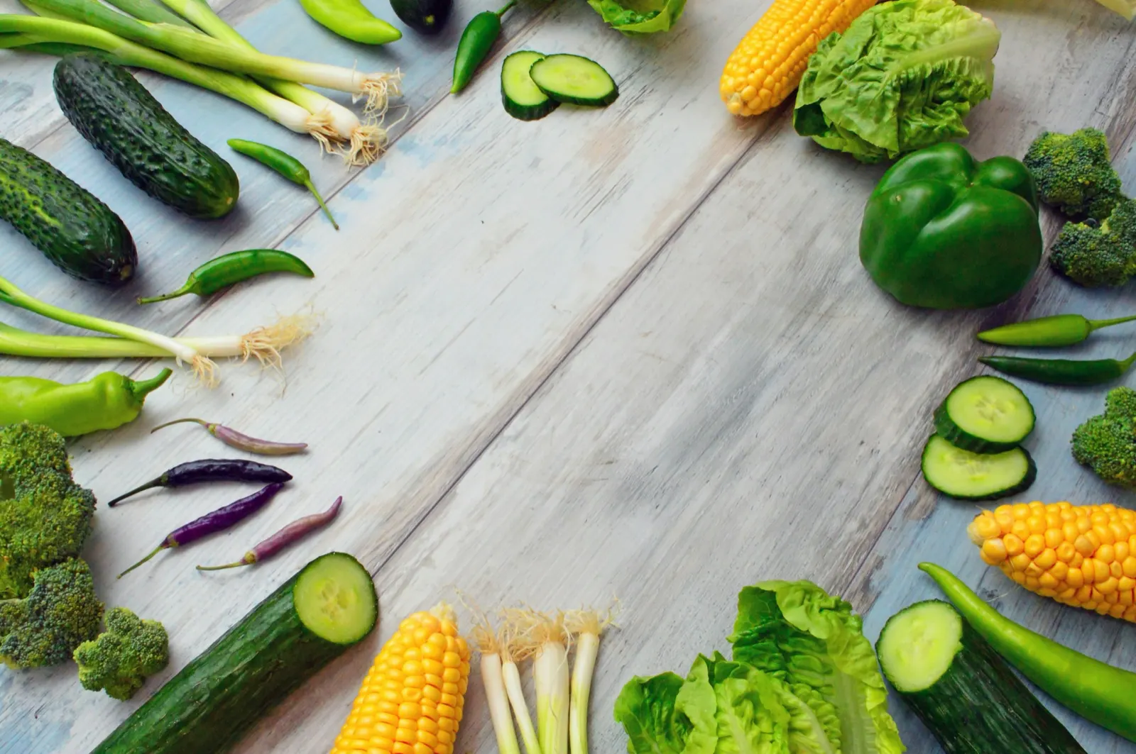 Fresh vegetables arranged on a pale wooden surface